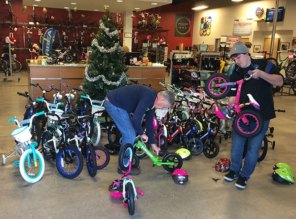 Redmond Cycle owner Ernie Estrin (left) and employee Braydon Kahler get bicycles donated by customers through the store’s rewards program ready to load into a trailer to be sent to Toys for Tots in Puyallup.