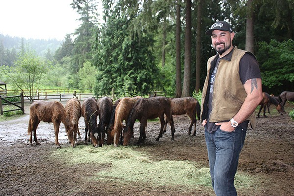Joe Tafoya stands near a herd of wild horses he and his wife’s family are caring for at their ranch east of Redmond.