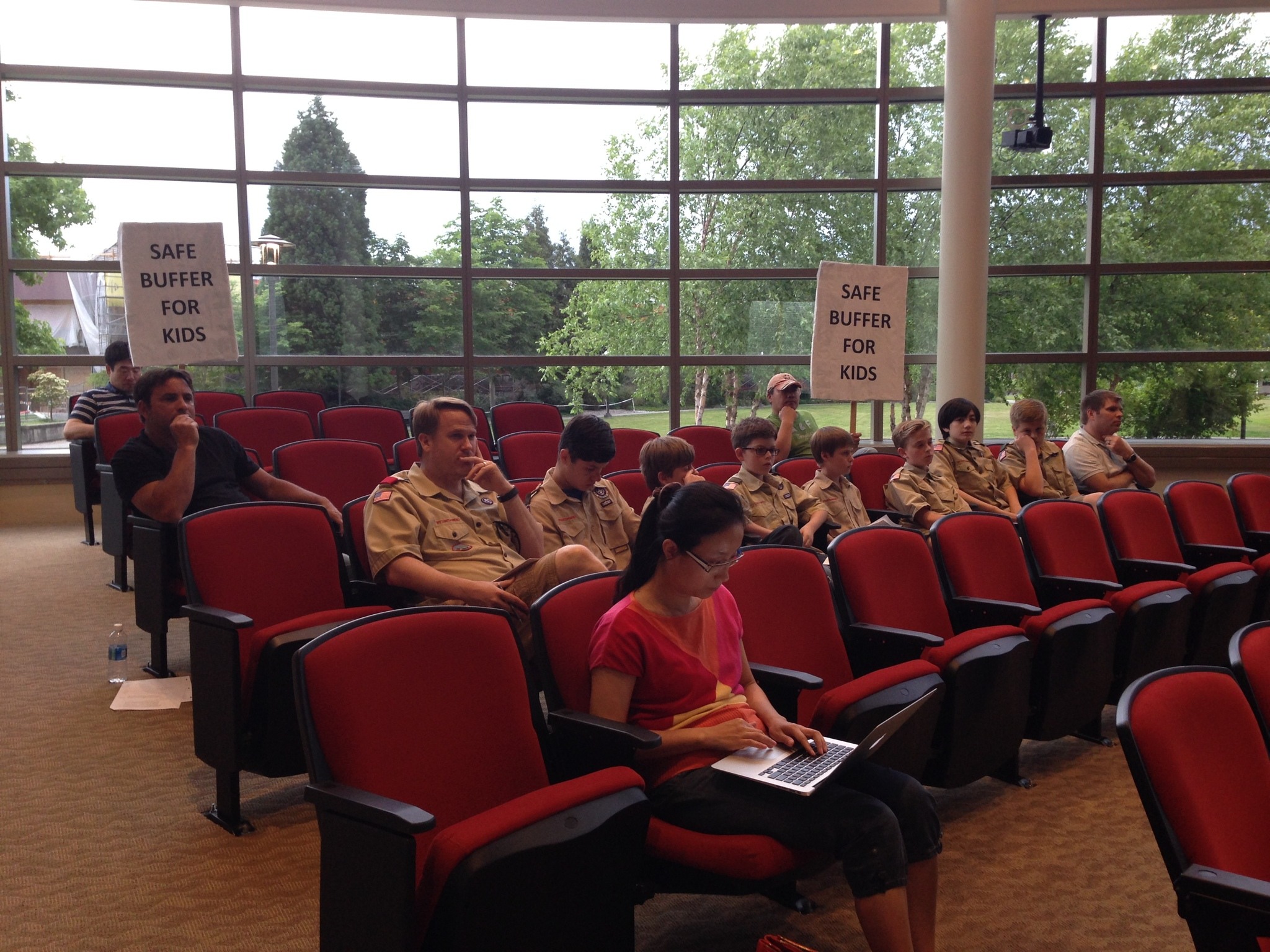 People hold up signs at Tuesday’s City Council meeting to protest allowing marijuana retail stores in Redmond. Samantha Pak