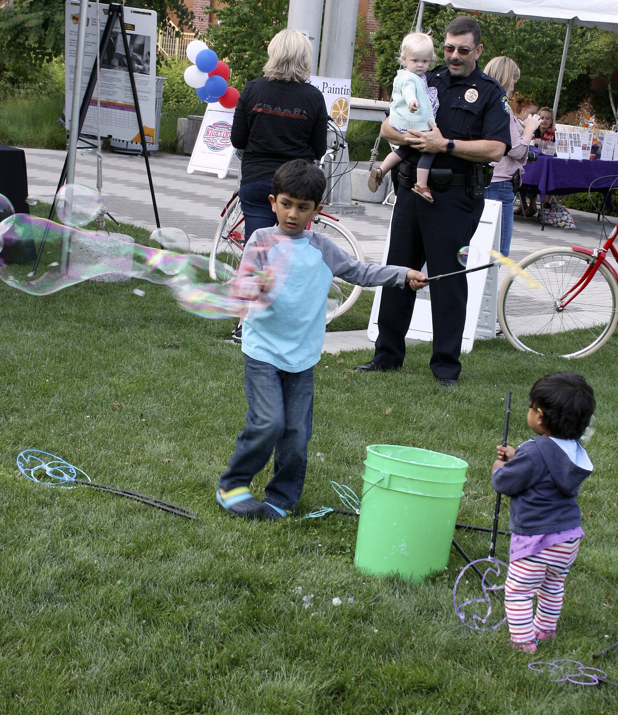 Kabir Seher plays with bubbles while Nathany Seher watches during Tuesday’s National Night Out Against Crime party at the Redmond Central Connector. Redmond Police Department Cmdr. Charlie Gorman checks things out with his granddaughter in the background. There were about 60 block parties in Redmond. Andy Nystrom