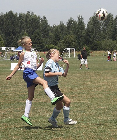 Crossfire Premier Soccer Club player Paris Moore (left) goes up for a header against a Seattle United player during a U12 match last Friday during the Nike Crossfire Challenge at 60 Acres.