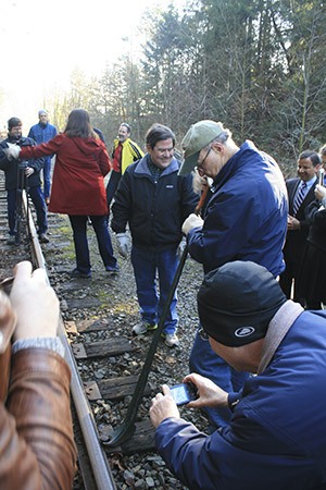 Bellevue Mayor John Stokes removes a railroad spike from the old BNSF rail line at the Kirkland and Bellevue boundary on Jan. 8.