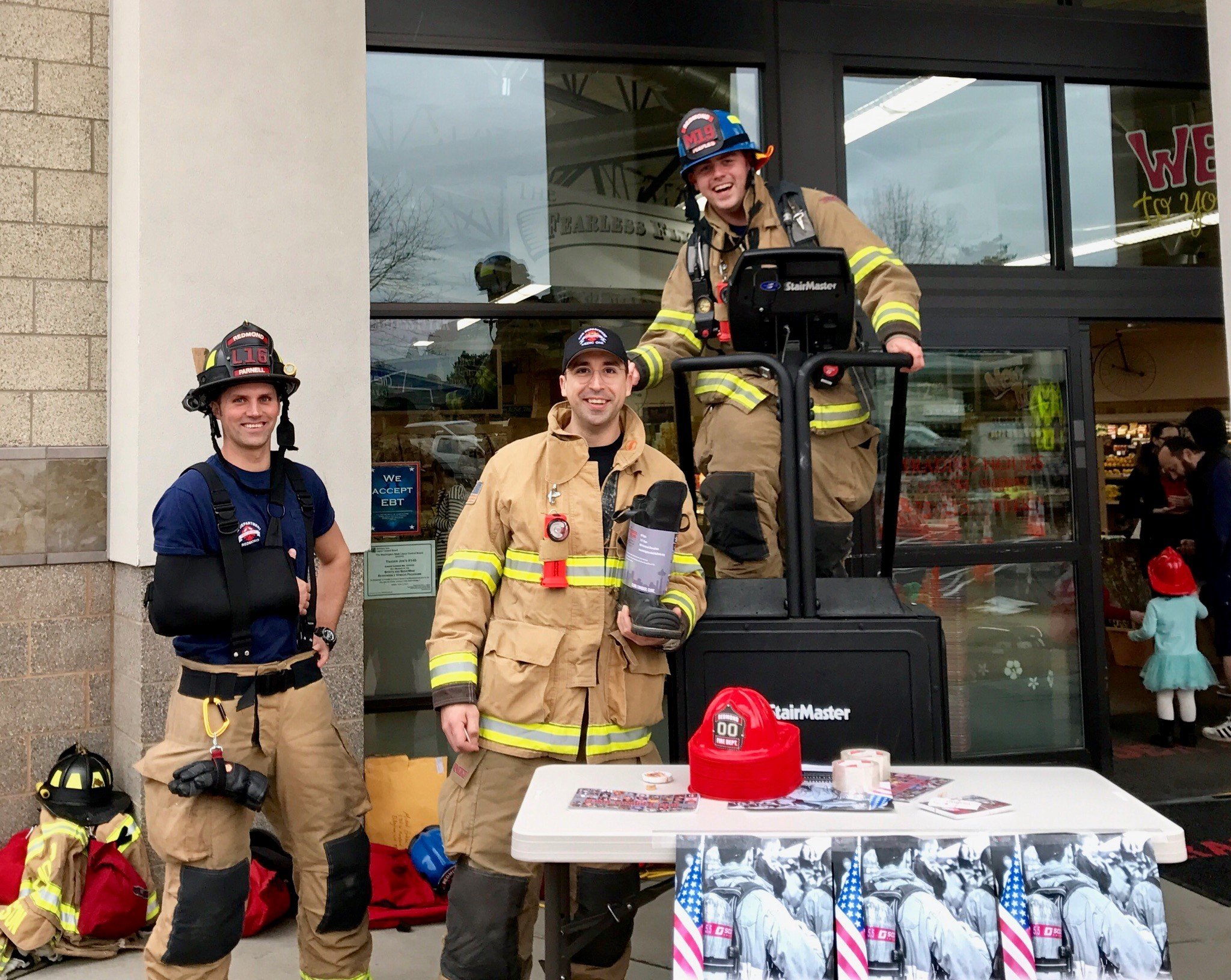 Redmond firefighter/paramedic Josh Peeples stair climbs, firefighter/paramedic Andrea DeCaro holds the boot and firefighter/EMT Tyler Parnell stands at left at Trader Joe’s. Courtesy photo