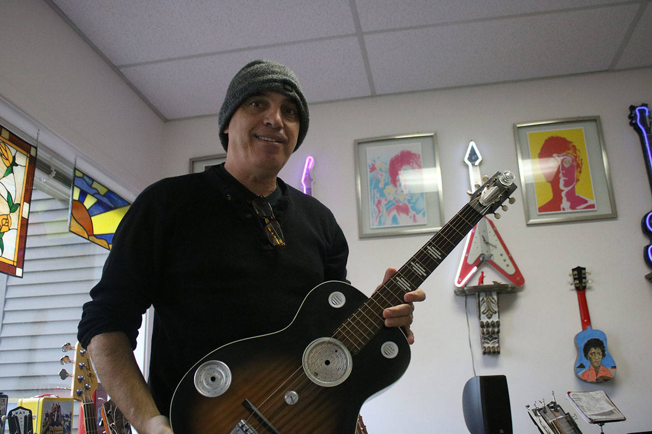 Dave Head holds a Stella guitar that is made with pieces of a coffee grinder. It has modifications that give it acoustic internal reverb. Aaron Kunkler/Redmond Reporter