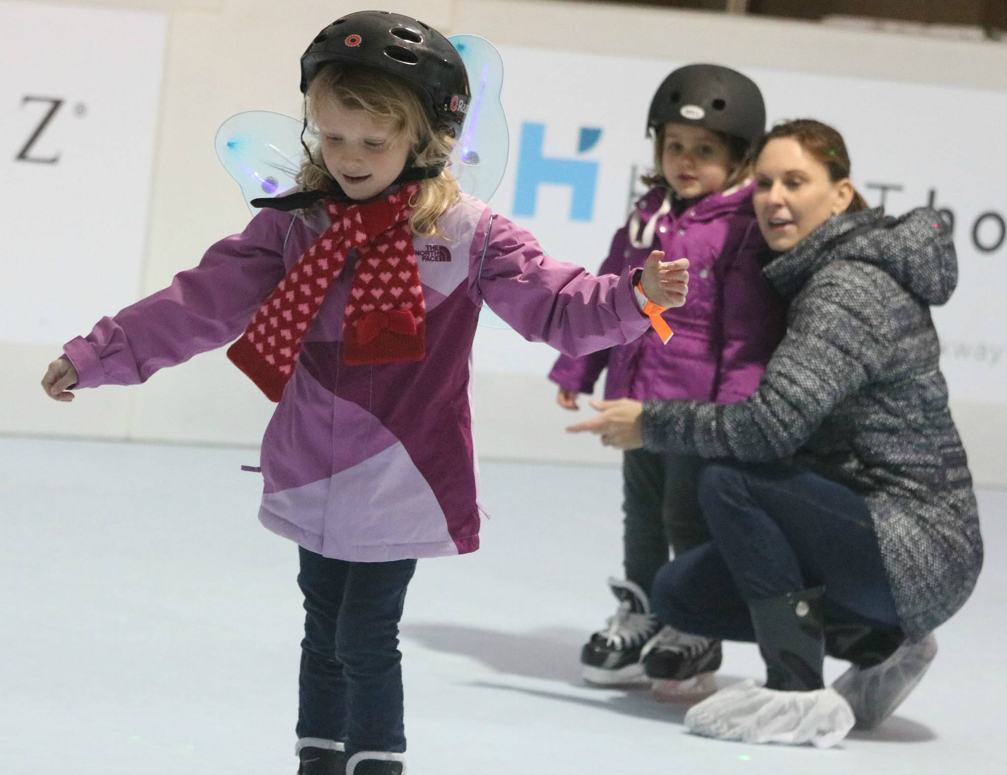 Ainsley Craig, front, skates on the Redmond Town Center synthetic rink tonight while her mom, Michelle, and sister, Vivienne watch.