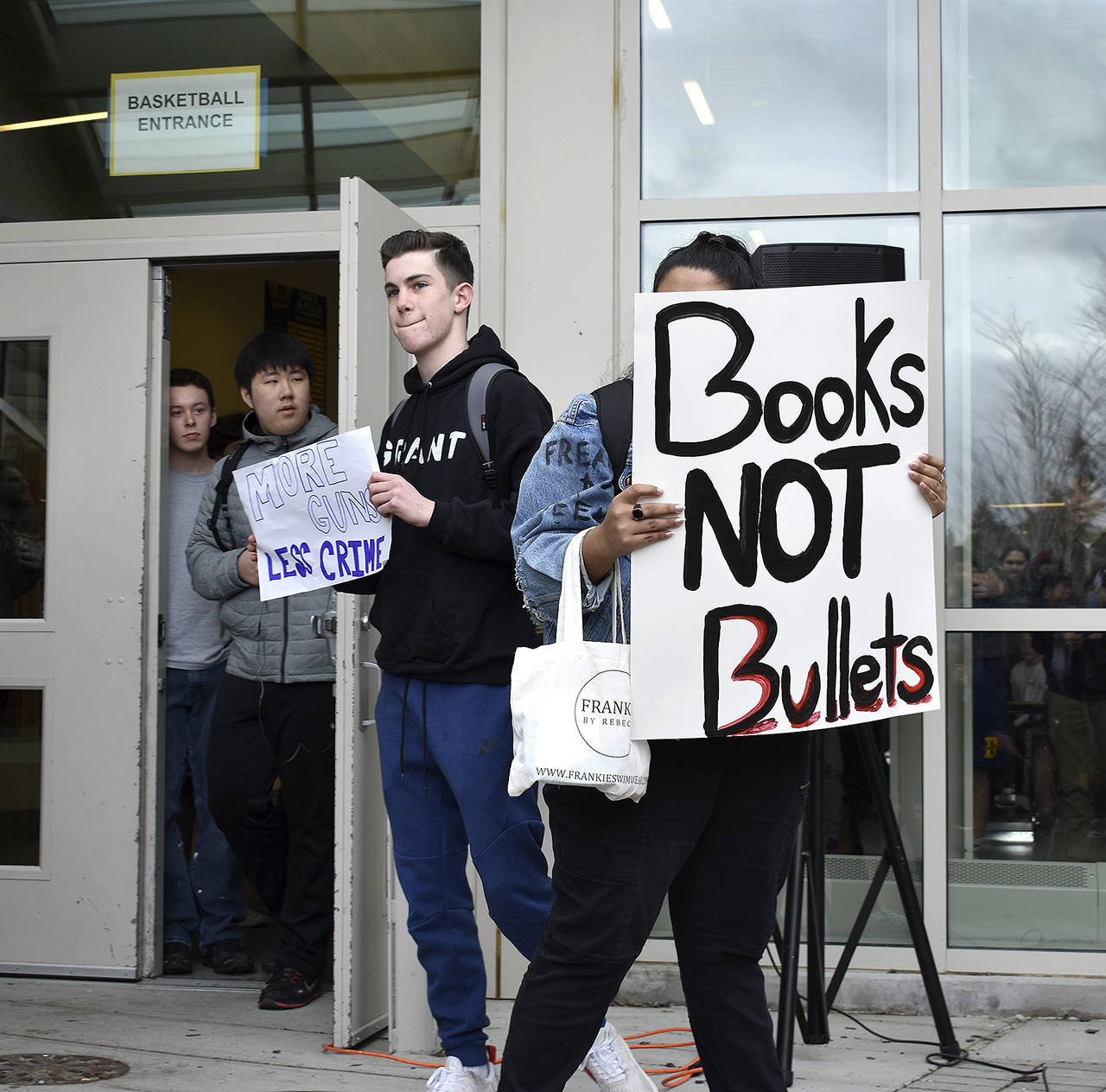 Bellevue High School student Charlie Kern holds a sign calling for “more guns, less crime” as another student holds a sign that reads “books, not bullets.” The walkout was student-led and students were able share their opinions and have a dialogue with one another. Raechel Dawson/staff photo