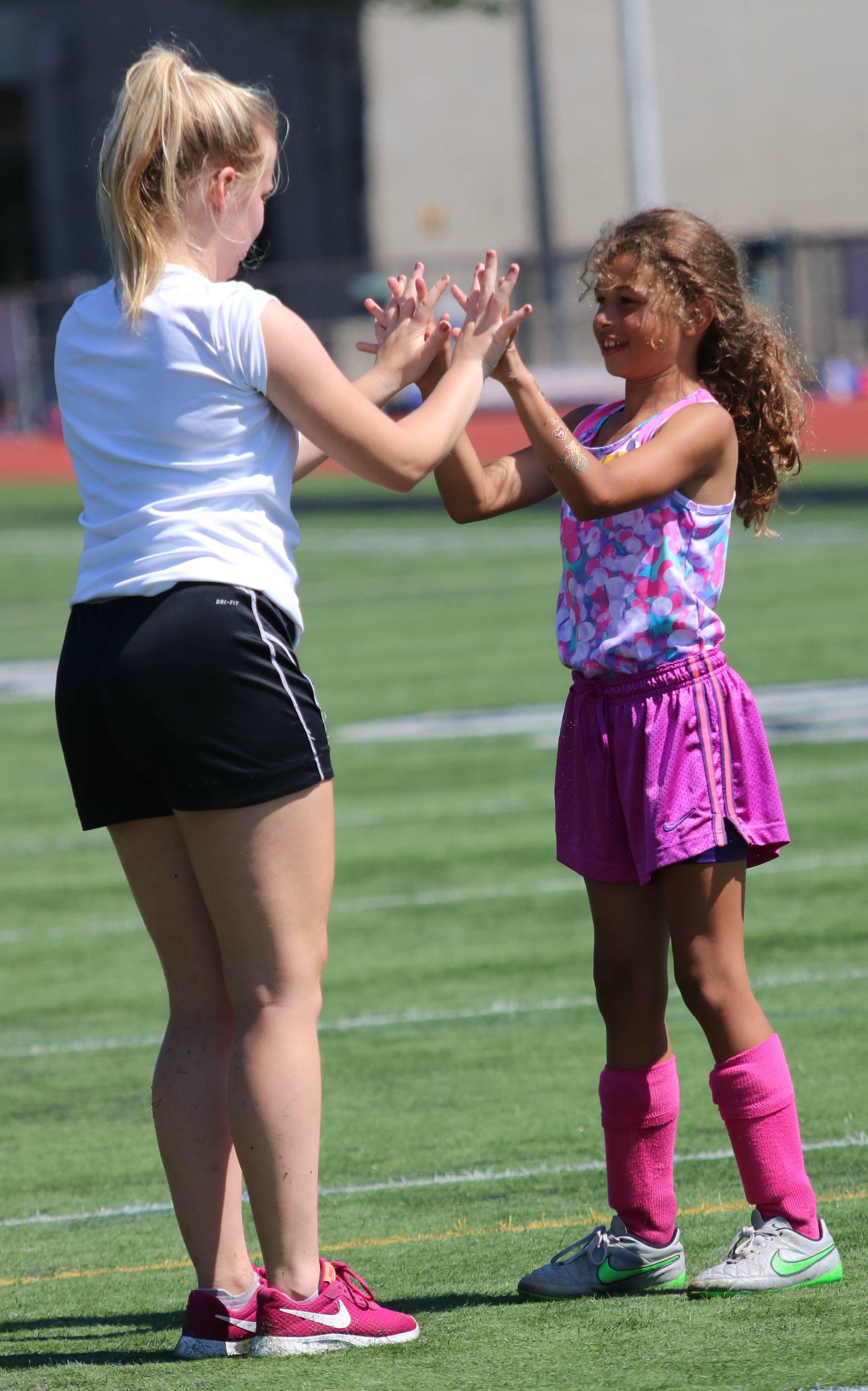 Camper Daisy Walker in pink and Redmond High player Ella Polly bond at camp. Andy Nystrom / staff photo