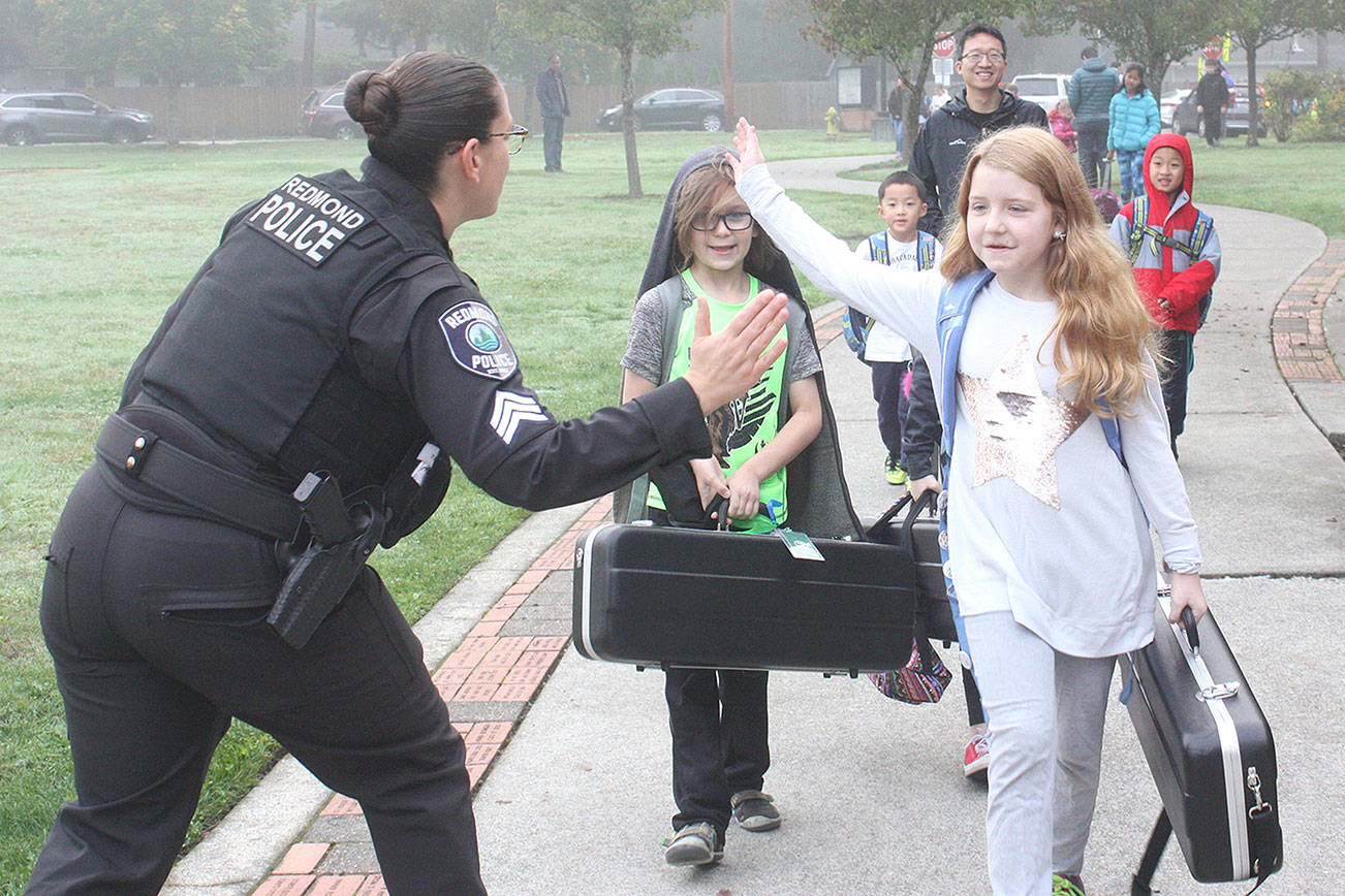 A Redmond police officer high fives Horace Mann Elementary students on International Walk to school Day on Oct. 10. Thousands of schools across the country, including 10 Redmond schools, participated in the 22nd Annual Walk to School Day. Redmond students helped reduce neighborhood traffic congestion and local air pollution by walking, biking, carpooling or riding the school bus. International Walk to School Day is facilitated as a part of Redmond’s SchoolPool program. The program works with schools to provide education on safety topics and events like Walk and Bike to School Days to encourage healthy behaviors for students and also rewards local students and schools for reducing the number of drive-alone trips to school. Stephanie Quiroz/staff photo.