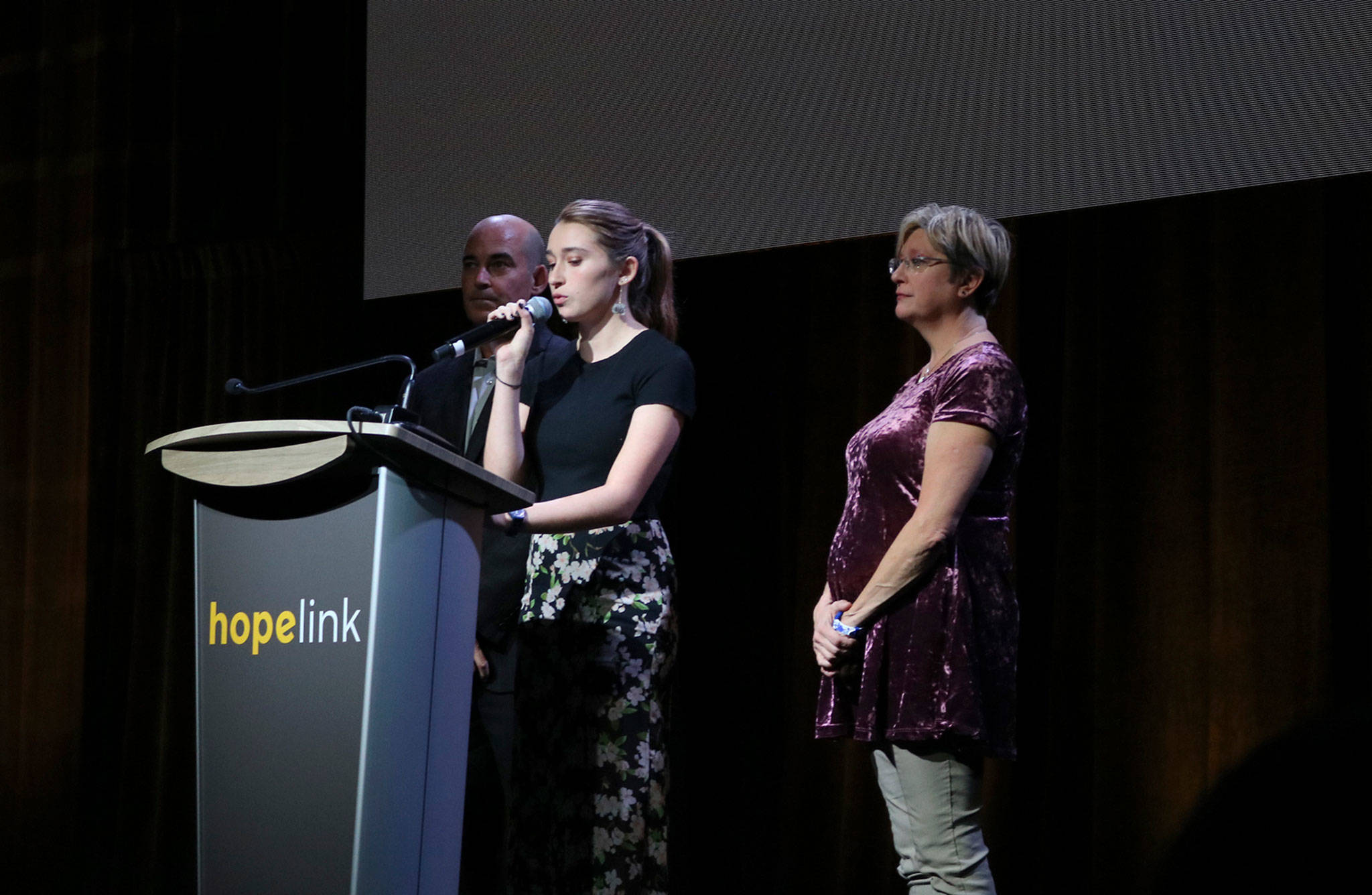 Zelda Shirk, a junior at Redmond High School, speaks at Hopelink’s Reaching Out luncheon on Oct. 15 with her parents and event co-chairs, Jeff and Lynette Shirk. Katie Metzger/staff photo