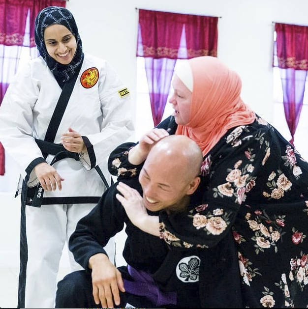 Fauzia Lala watches as one of her students practices self-defense with Bellevue police officer Craig Hanaumi. Photo via Instagram