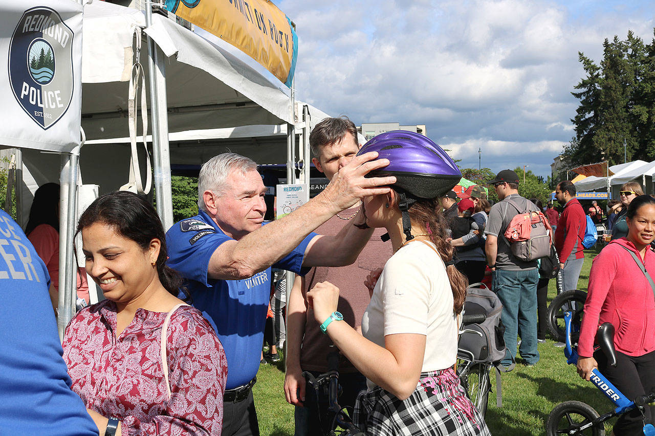 Redmond Police Department volunteer assures a helmet on a customer on May 17. Stephanie Quiroz/staff photo