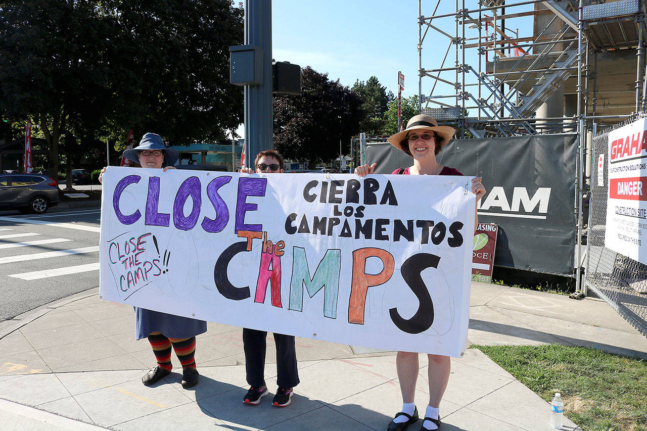 From left, Nicole Ricca, Joan Yim and Amanda Karim hold sign that says “Close the Camps” at the July 12 Lights for Liberty Vigil.