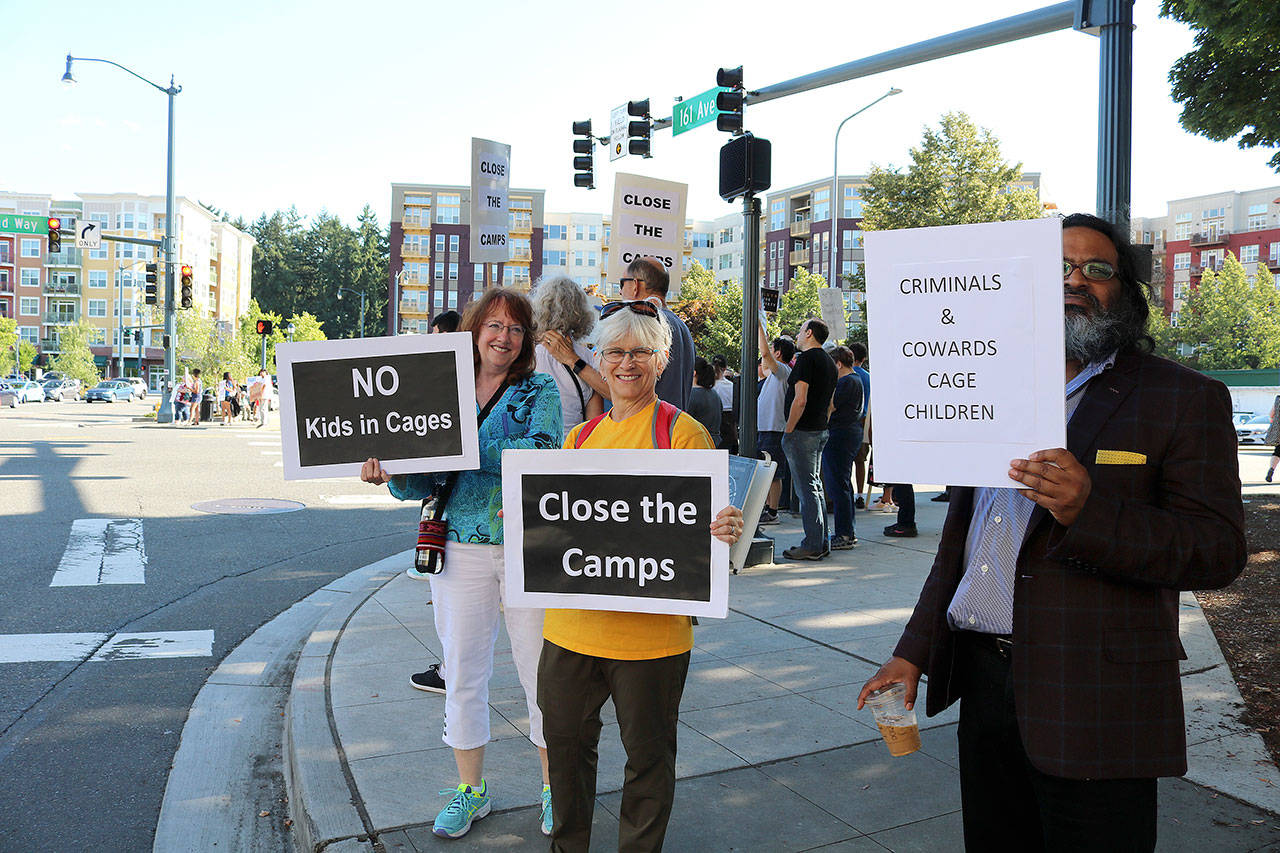 From right, Romi Mahajan, Judy Jesiolowski and Trish Watson hold signs at the intersection of Redmond Way and 161st Avenue Northeast, near Downtown Park, on July 12.