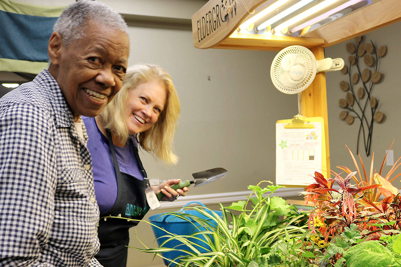 Resident Julia Hardwick and educator Lucy Nesse all smiles as they plant a daisy flower in the mobile garden. Stephanie Quiroz/staff photos