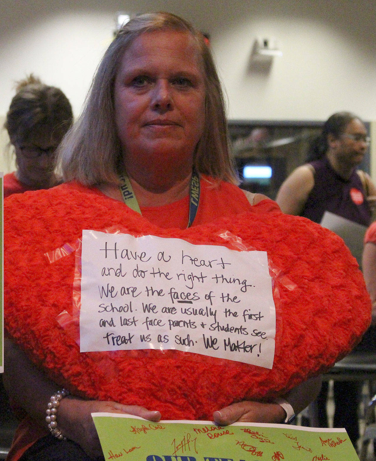 Peg Jatekar, a healthroom secretary at Laura Ingalls Wilder Elementary School, held a plush heart with a handwritten note attached at the school board meeting. The note read “Have a heart and do the right thing…We are the faces of the school. We are usually the first and last face parents and students see. Treat us as such. We matter!” Madison Miller/staff photo
