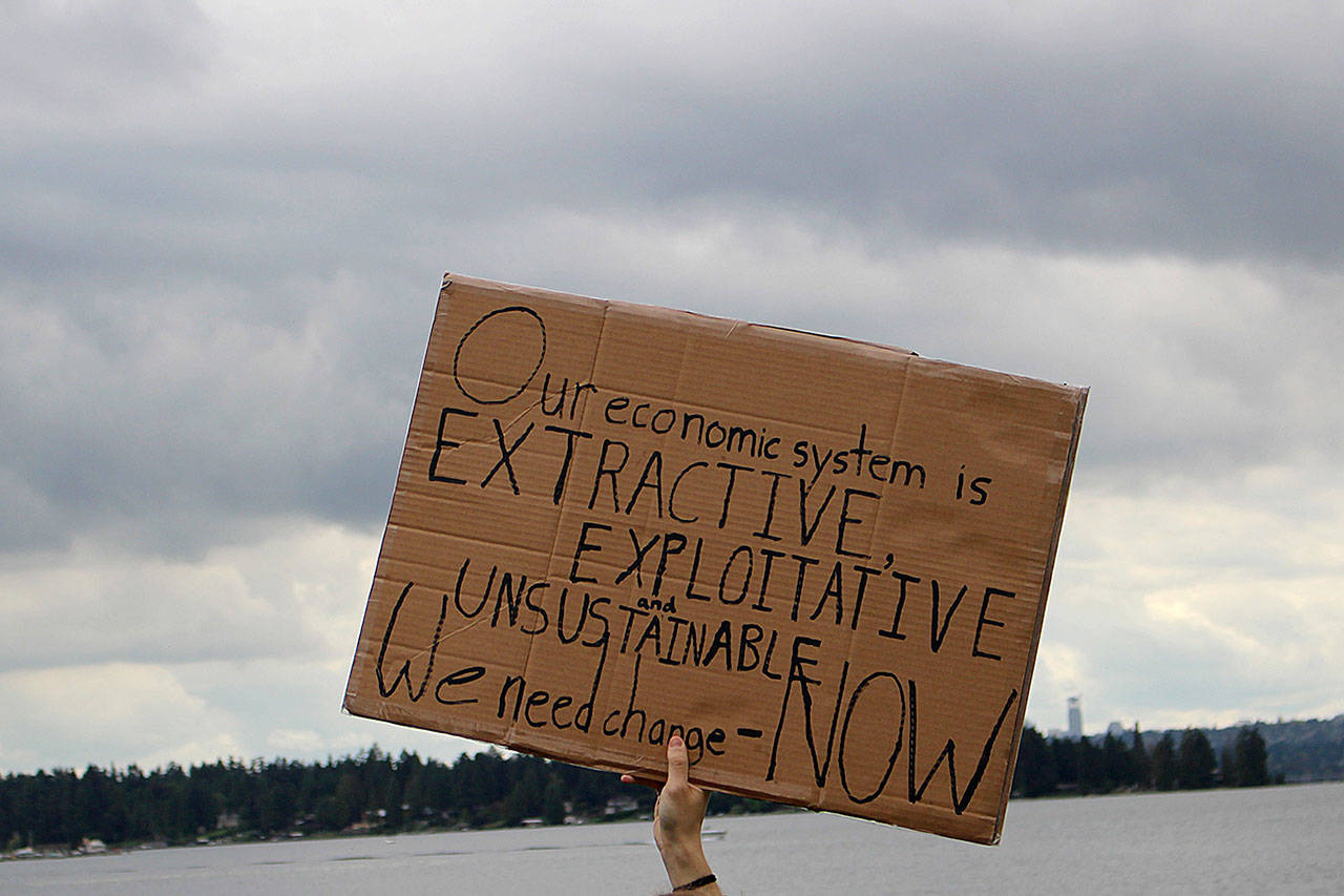 A sign at the Kirkland climate strike at Houghton Beach Park Friday. “Our economic system is extractive, exploitative and unsustainable. We need change — Now.” Madison Miller/staff photo