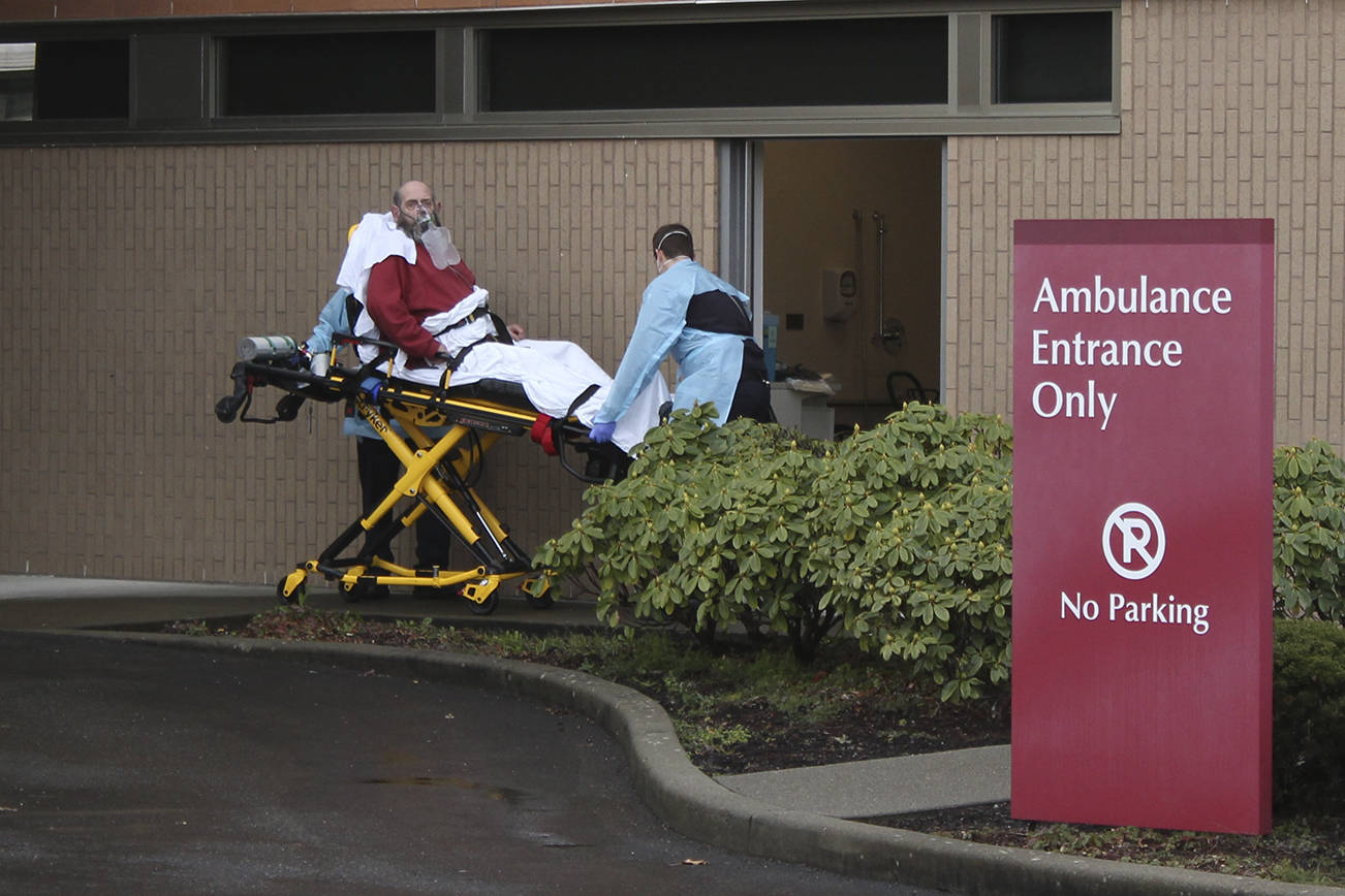 At St. Elizabeth Hospital in Enumclaw, a patient is taken from an ambulance through a small door marked “decontamination” on March 23. It was unclear whether the patient was suspected of being infected with COVID-19. (Photo by Ray Miller-Still/Sound Publishing)