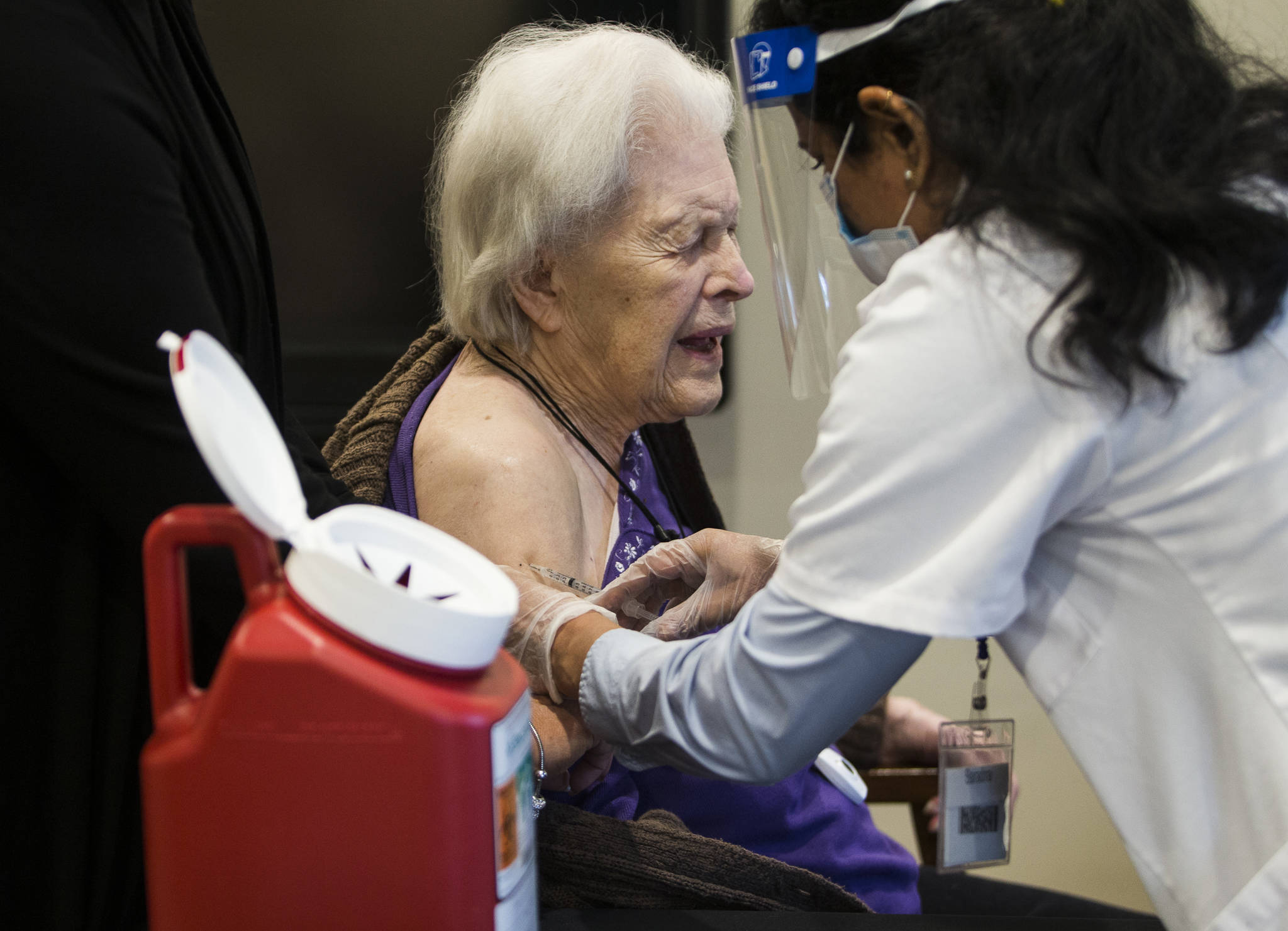 Jackie Hoernor winces as she gets her Pfizer COVID-19 vaccination during a Walgreen’s Vaccine Clinic at South Pointe on Friday, Feb. 12, 2021, in Everett, Washington. (Sound Publishing file photo)