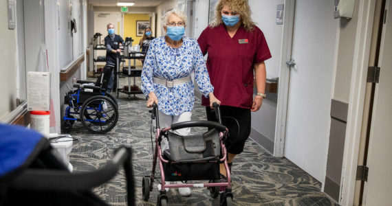 CNA Nina Prigodich, right, goes through restorative exercises with long term care patient Betty Long, 86, at View Ridge Care Center on Friday, Feb. 10, 2023 in Everett, Washington. (Olivia Vanni / The Herald)