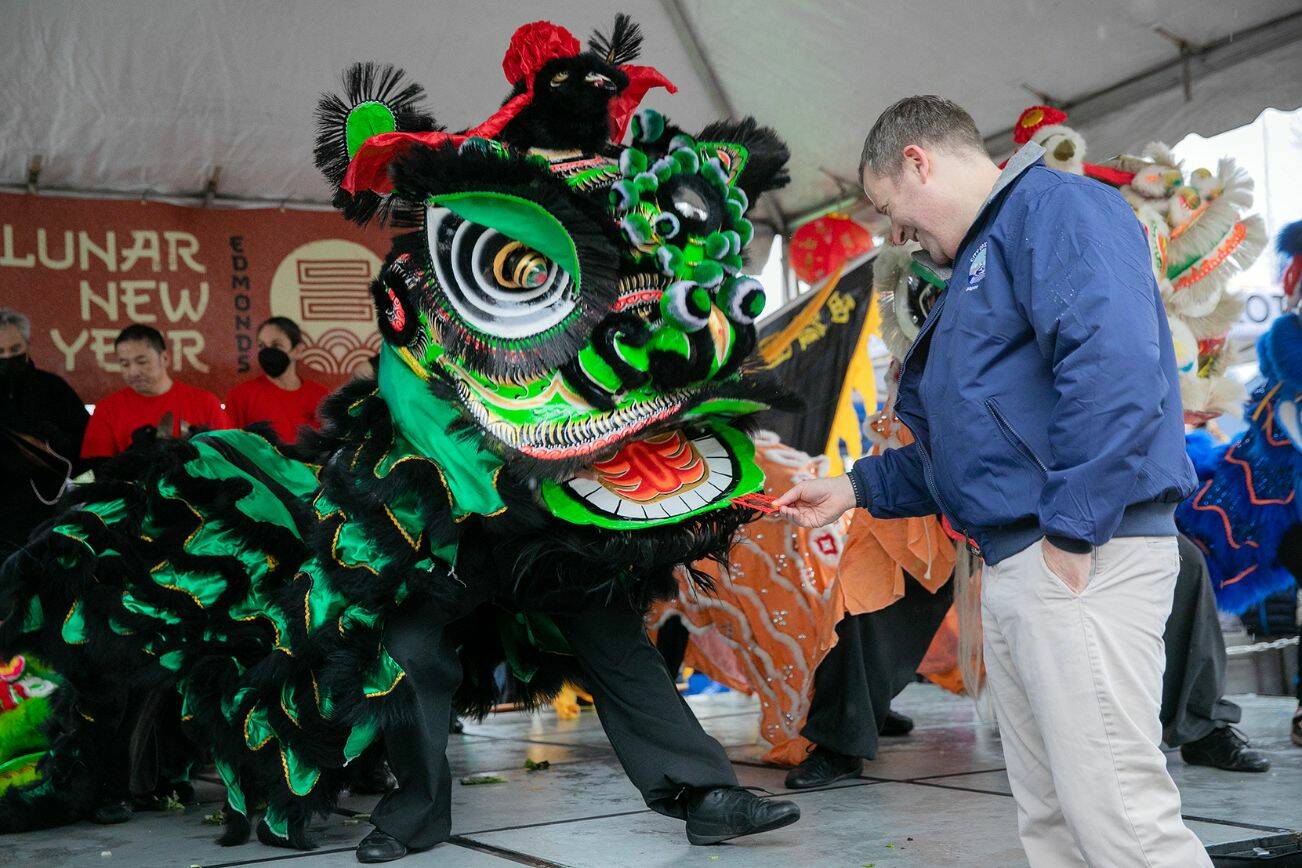 Edmonds Mayor Mike Nelson rewards a lion dancer with a traditional red envelope during a celebration of the Lunar New Year on Saturday, Jan. 21, 2023. Photo by Ryan Berry / The Herald