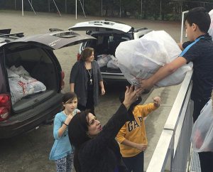 Anas Alqinawi (right) hands over a bag of donated items to his mother Sahar Albobo. The items were part of a donation drive at Einstein Elementary to raise money for the student council.