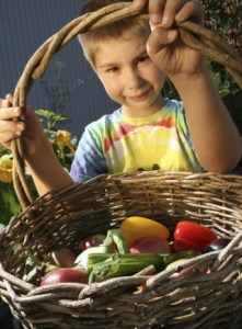Explorer Community School student Mychal Miller shows off a collection of vegetables grown in the school's community garden. Explorer