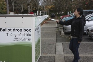 A voter drops off her ballot yesterday at the Redmond Senior Center.