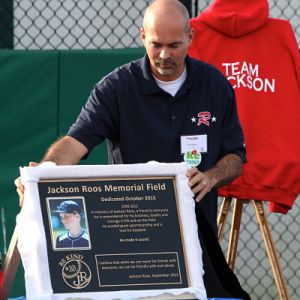 Redmond North Little League president J.D. Klein unveils a plaque to dedicate Jackson Roos Memorial Field at Redmond Ridge Park on Oct. 4.