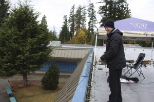 Evergreen Middle School principal Sean Cassidy lowers a bag on a rope filled with signed paperwork to a staff member in the courtyard below as he works from the school's roof on Wednesday.