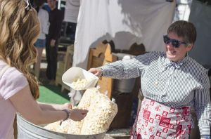 Julianne (last name withheld) pours kettle corn for a customer at yesterday's Redmond Saturday Market downtown. It was the opening day of the market's 38th season