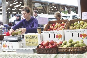 Hannah Waterman weighs pears before making cider at the Martin Family Orchards booth at the May 3 Redmond Saturday Market.