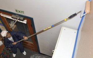 Redmond resident Leona Locke uses a long roller to paint the high walls of a preschool classroom during the Friday (Sept. 24) Day of Caring cleanup at Encompass
