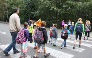 Students and their parents make their way across a crosswalk as they approach Albert Einstein Elementary School as part of Walk to School Day.