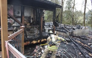 Redmond firefighter David Watson works to douse and destroy smoldering spots from a fire that destroyed a garage