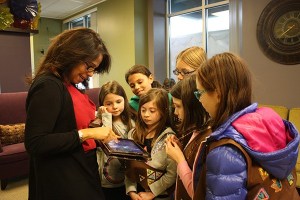Suzy Burke-Myers (left) shows members of Girl Scout Troop 44271 pictures from her trip to Egypt. The girls donated gifts for her to give to a girls’ orphanage in her family’s hometown.