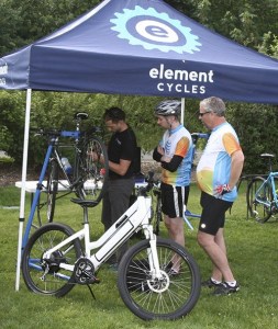 Two Bike Bash attendees watch as an Element Cycles employee works on their bikes last Friday.