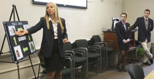Redmond High School DECA student Kelly Weiss (left) explains her team's marketing plan for Eddie Bauer to Lake Washington School District officials