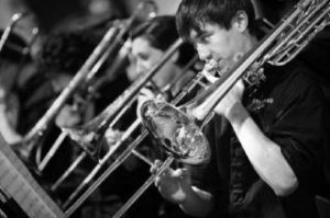 ABOVE: Kevin Bush plays the trombone with the Overlake Jazz band as they perform “Beyond the Sea” in the fieldhouse during Founder’s Day at The Overlake School last week. RIGHT: Rae Parks watches band director Steve Mraz as she sings with the Overlake Jazz band as they perform “A Foggy Day.”