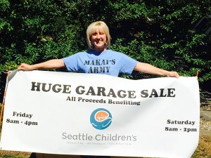 Organizer Ginger Bryant proudly displays the garage sale sign for the huge event that took place Aug. 21-22 in Redmond to support Seattle Children’s Hospital.