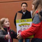 Montessori Children&rsquo;s House first-grader Thia Berta, left, receives a box of donations from third-grader Alex Imes while parent chaperone Tom Lee stands by. Courtesy of Montessori Children&rsquo;s House, MCHkids.com