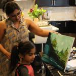 Haritha Kamakoti holds up the canvas as her daughter, Ira Ganjikunta, 6, puts the finishing touches on a painting at their Redmond home. CATHERINE KRUMMEY/Kirkland Reporter