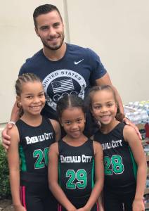 Two-time United States Olympic gymnast Jake Dalton poses with sisters Melina, Mia and Maya Prescod at Emerald City Gymnastics Academy in Redmond last Saturday to help celebrate National Gymnastics Day. The Prescods are members of Emerald City&rsquo;s Junior Olympic team. Courtesy of Sandy Flores