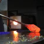 Brad Stearns, the studio manager for Redmond School of Glass, rolls a molten ball of glass over smaller chunks of colored glass that will be melted together into a pumpkin. Aaron Kunkler/Redmond Reporter