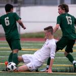 Snohomishs Liam Raney slides to dislodge the ball from Redmonds Victor Araujo (left) with Jacen Stein trailing in the quarterfinals Friday night at Veterans Memorial Stadiums in Snohomish on May 18. (Kevin Clark / The Herald)