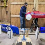 As her grandfather, Rich McCalib, wipes down the car, Alexie Crabtree removes a decal from her soap box car. (Andy Bronson / The Herald)