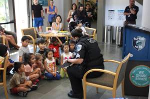 Sergeant Julie Beard reads Officer Buckle and Gloria, promoting safety to local children at the Little Free Library opening. Kailan Manandic, Redmond Reporter