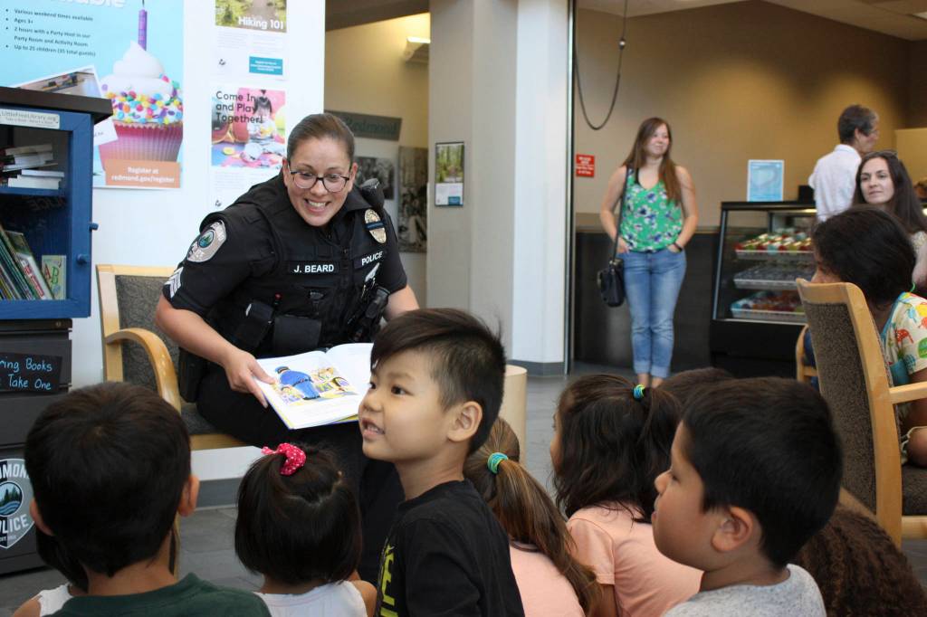 Sergeant Julie Beard reads Officer Buckle and Gloria, promoting safety to local children, while sitting next to the Little Free Library. Kailan Manandic, Redmond Reporter