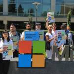 Activists pose in front of a sign at the Microsoft visitors center as they turned in 300,000 signatures asking the corporation to stop supporting Immigration and Customs Enforcement through a nearly $20 million contract. Aaron Kunkler/Staff photo