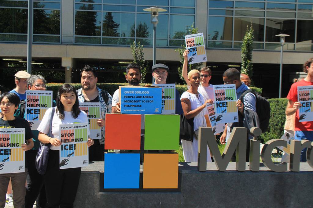 Activists pose in front of a sign at the Microsoft visitors center as they turned in 300,000 signatures asking the corporation to stop supporting Immigration and Customs Enforcement through a nearly $20 million contract. Aaron Kunkler/Staff photo