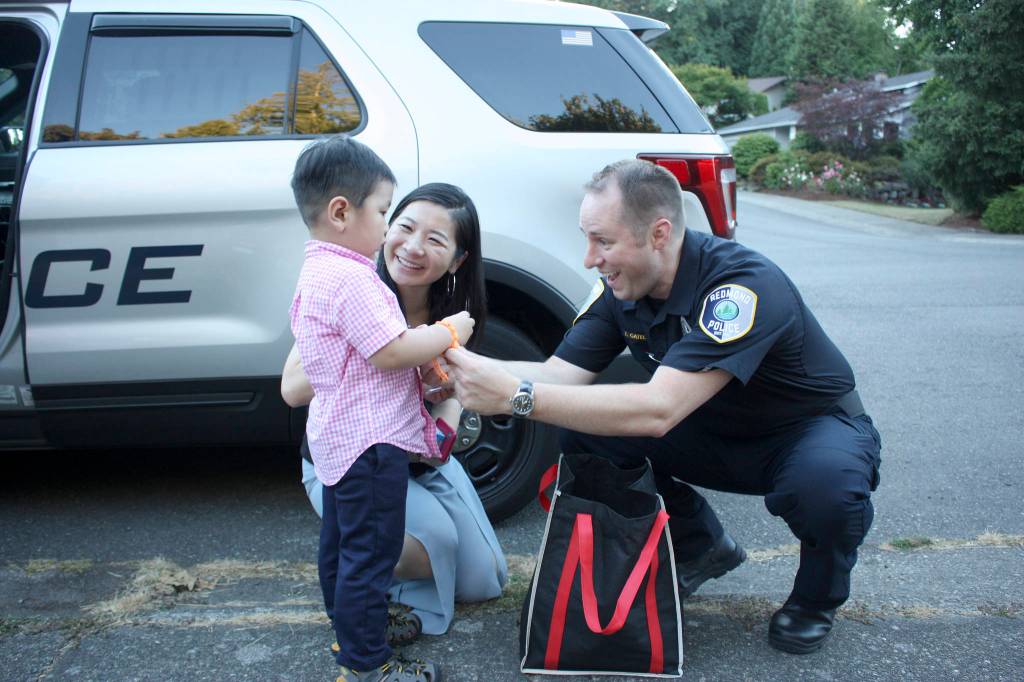 Lieutenant Tim Gately gives small gifts to Aaron Yang at one of the 65 neighborhood block parties throughout Redmond. Kailan Manandic/Staff Photo